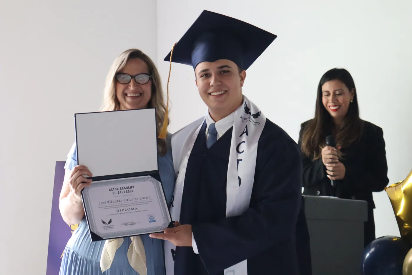 Shannon Falkenstein with the first graduate of Acton Academy El Salvador in cap and gown, holding his diploma
