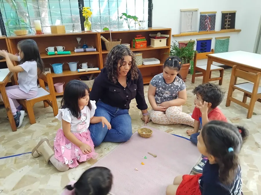 A guide sitting on the mat with the preschool circle