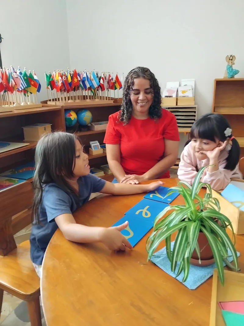 A guide and two young children working with the sandpaper letters