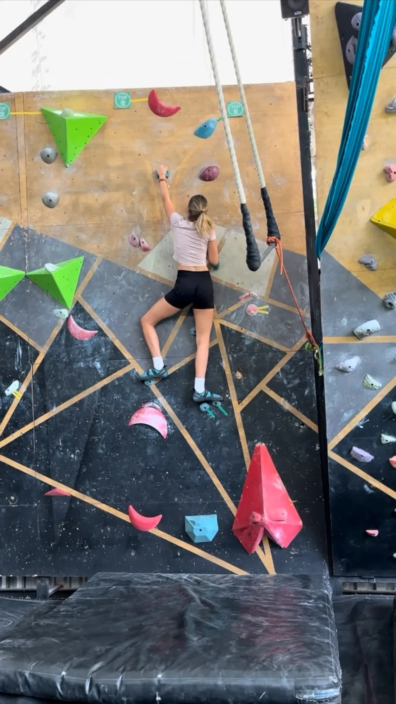 A learner from the Acton rock climbing team working her way up the wall at Move